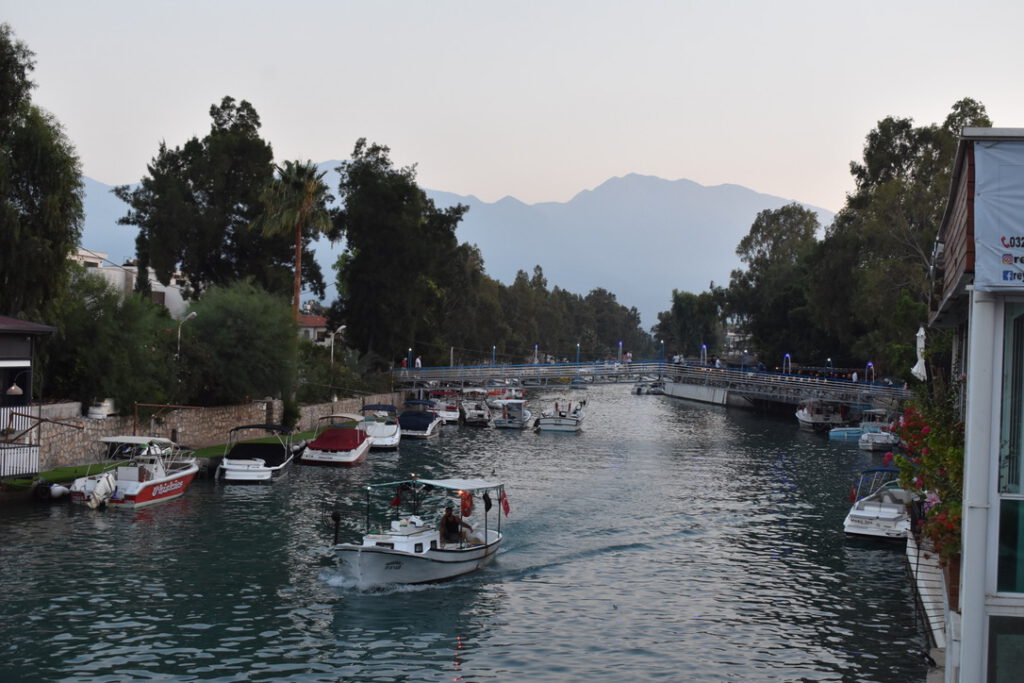Blick auf die Berge, die die Türkei von Syrien trennen, davor ein Fluss, auf dem mehrere Boote fahren