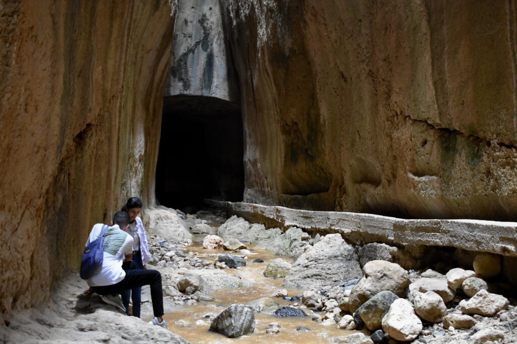 Zwei Reisende im Titus-Tunnel stehen am Rande des Flusses, der durch das Bauwerk fließt