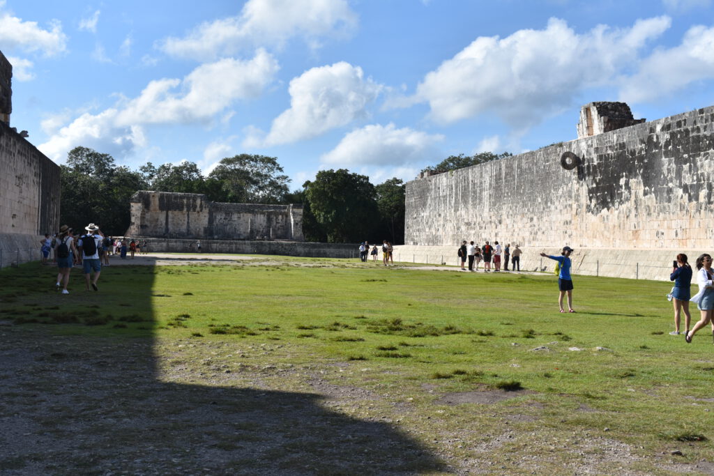 Menschen flanieren entlang der Maya-Bauwerke von Chichen Itza