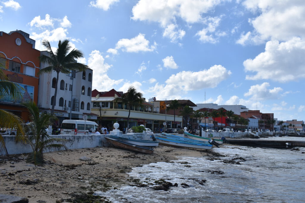 Boote an der Küste von Cozumel, im Hintergrund bunte Häuser