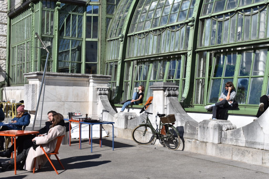 Menschen sitzen vor der Brasserie Palmenhaus in der Sonne