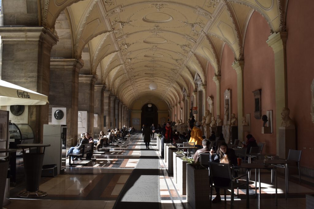 Studenten sitzen unter einer prachtvollen Arkade in der Wiener Universität