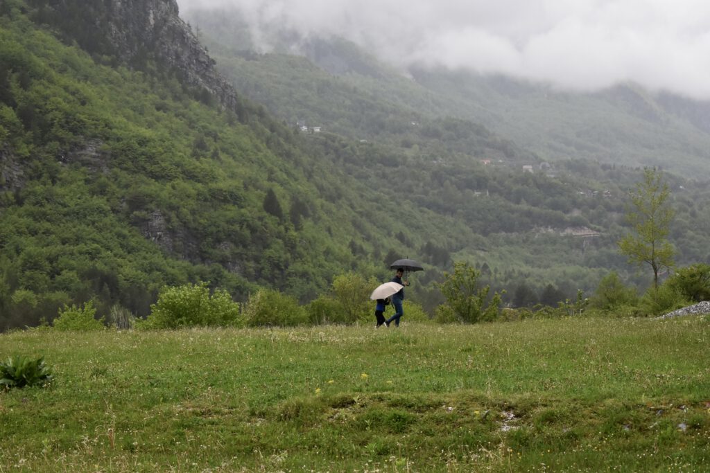Vater und Sohn mit Regenschirmen vor einer Berglandschaft