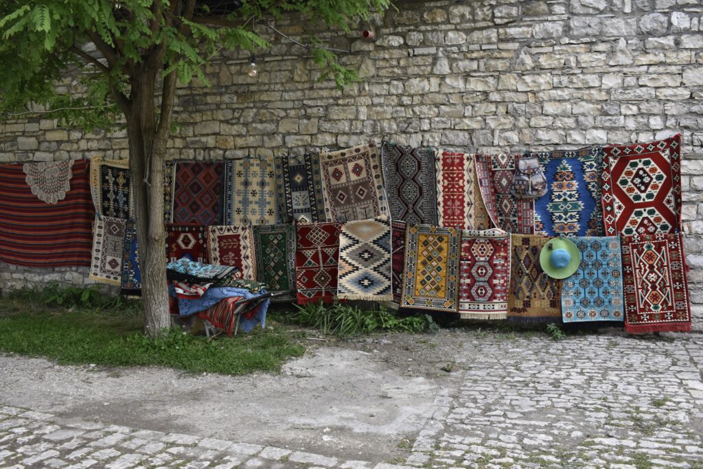 Teppiche hängen an einer Wand in der Burg von Berat