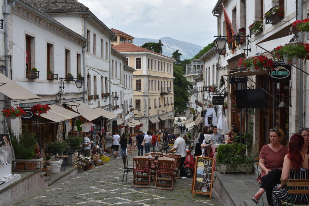 Menschen sitzen von den Restaurants in einer Seitenstraßen von Gjirokastra