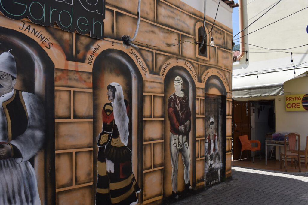 Street Art in Tirana: Traditionell gekleidete Menschen, gemalt an die Wand des "Oda Garden"-Restaurant
